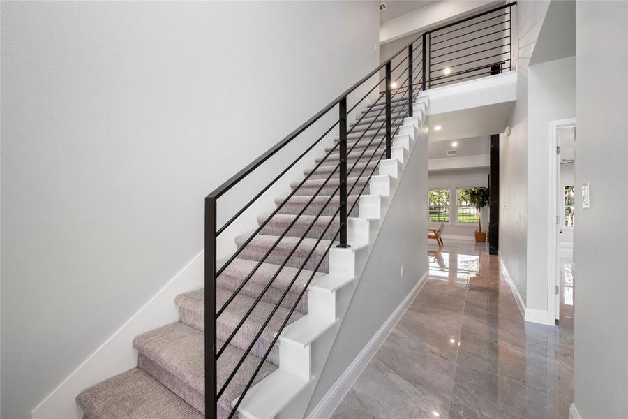 Stairway with a high ceiling, marble tiled flooring, and french doors