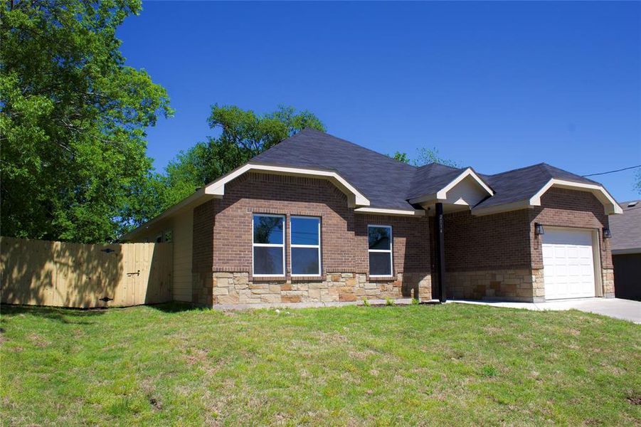 View of front of property featuring a garage and a front lawn