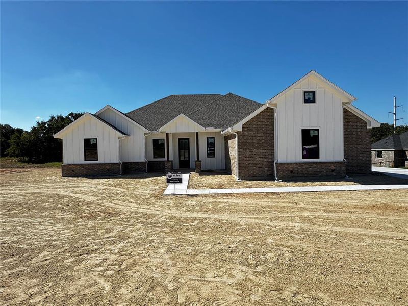 Modern inspired farmhouse with board and batten siding, covered porch, and a shingled roof
