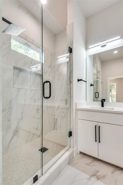 Bathroom featuring tile flooring, vanity, and a shower with door