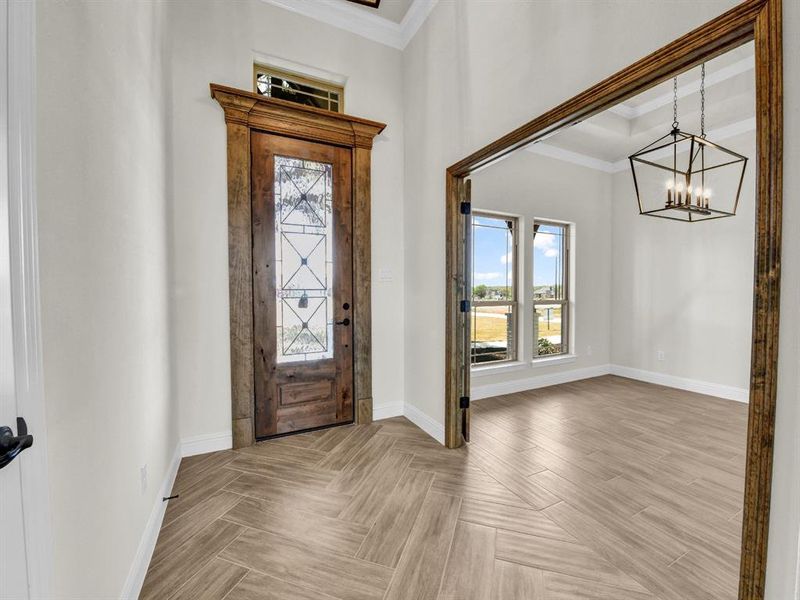 Entrance foyer featuring baseboards, a notable chandelier, parquet floors, and crown molding Entrance foyer featuring baseboards, a notable chandelier, parquet floors, and crown molding