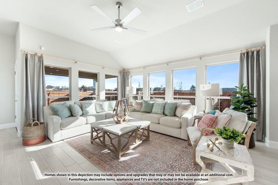 Bright living room with vaulted ceiling, ceiling fan, multiple windows, and neutral sofas on a patterned rug Bright living room with vaulted ceiling, ceiling fan, multiple windows, and neutral sofas on a patterned rug