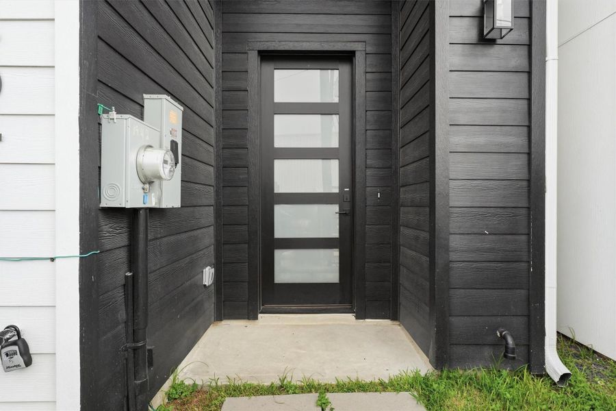 Modern covered entry with sleek contemporary door, horizontal panel detailing, and clean architectural lines creating a stylish first impression.