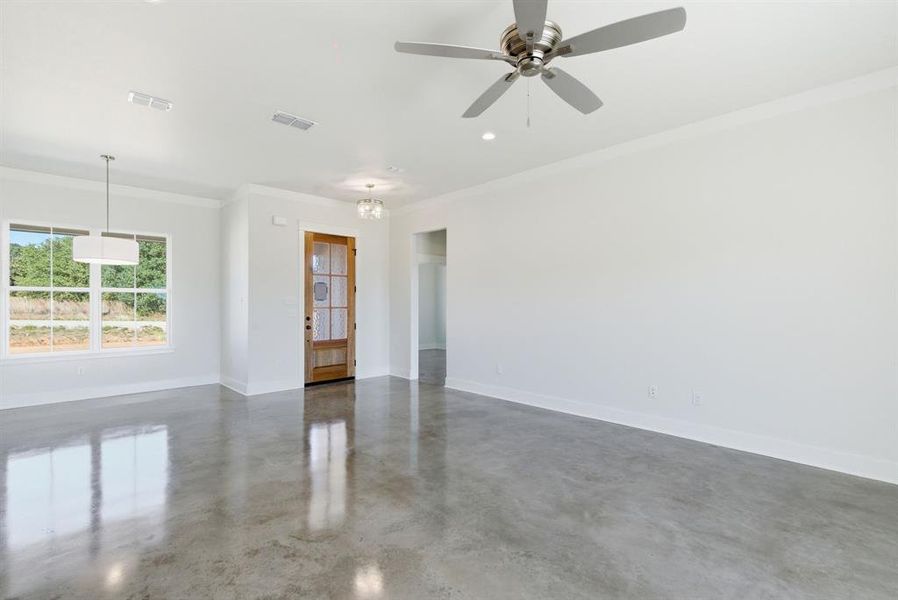 Empty room featuring ornamental molding, finished concrete flooring, a chandelier, and a ceiling fan