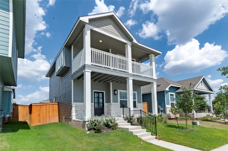 View of front of property with covered porch, stone siding, and a balcony View of front of property with covered porch, stone siding, and a balcony