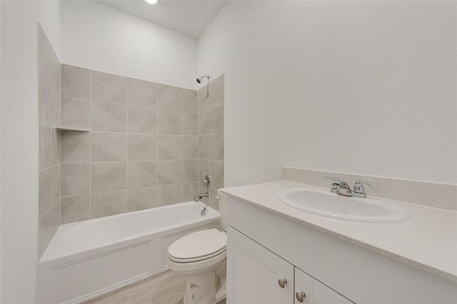 Full bathroom with hardwood / wood-style floors, vanity, toilet, and tiled shower / bath