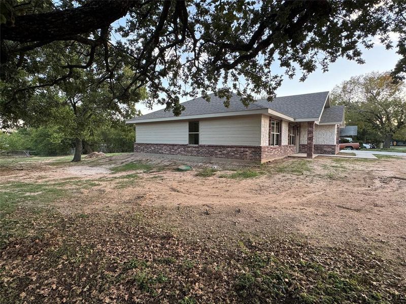 View of side of home with brick siding and a shingled roof