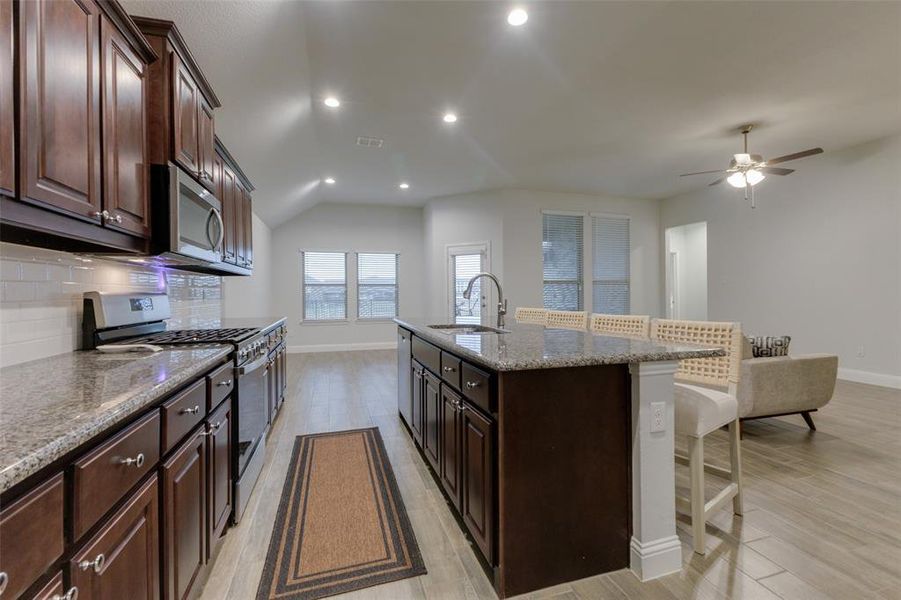 Kitchen featuring backsplash, sink, light wood-type flooring, and appliances with stainless steel finishes