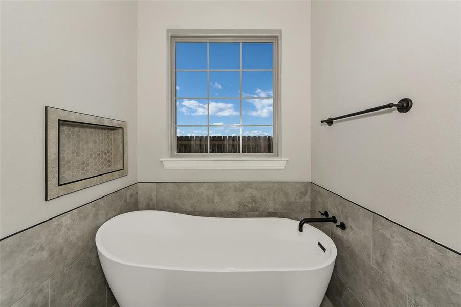Bathroom with tile walls, a freestanding tub, and a wainscoted wall