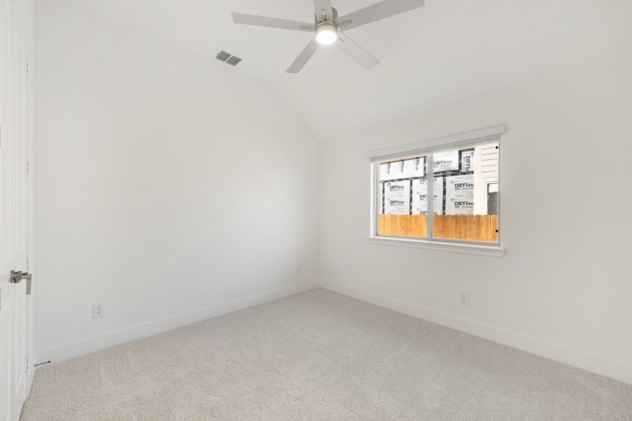 Empty bedroom with vaulted ceiling, ceiling fan, carpet flooring, and single window Empty bedroom with vaulted ceiling, ceiling fan, carpet flooring, and single window