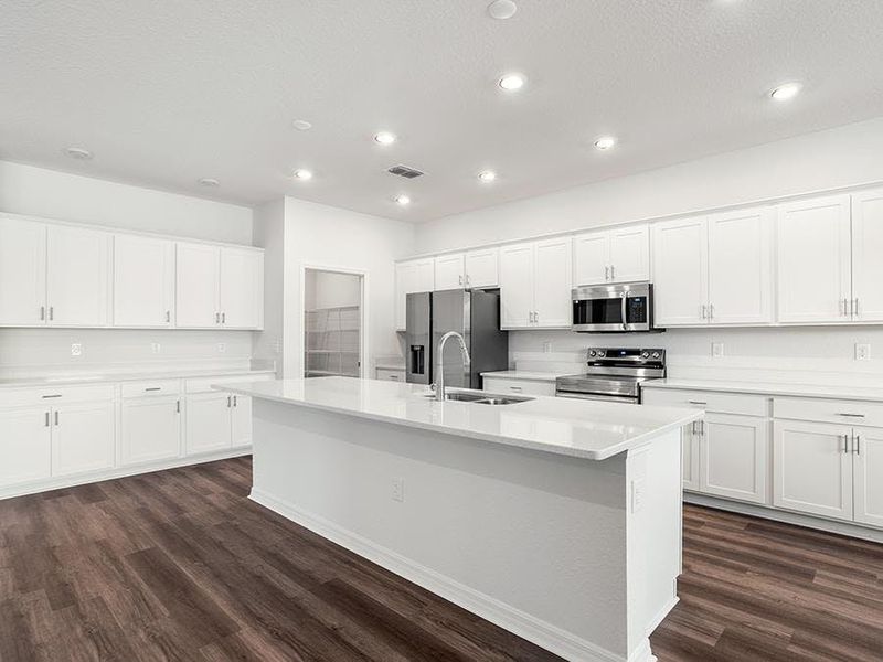 The spacious kitchen wows with a large island, bright lighting, and ample cabinet and counter space - Everly by Highland Homes