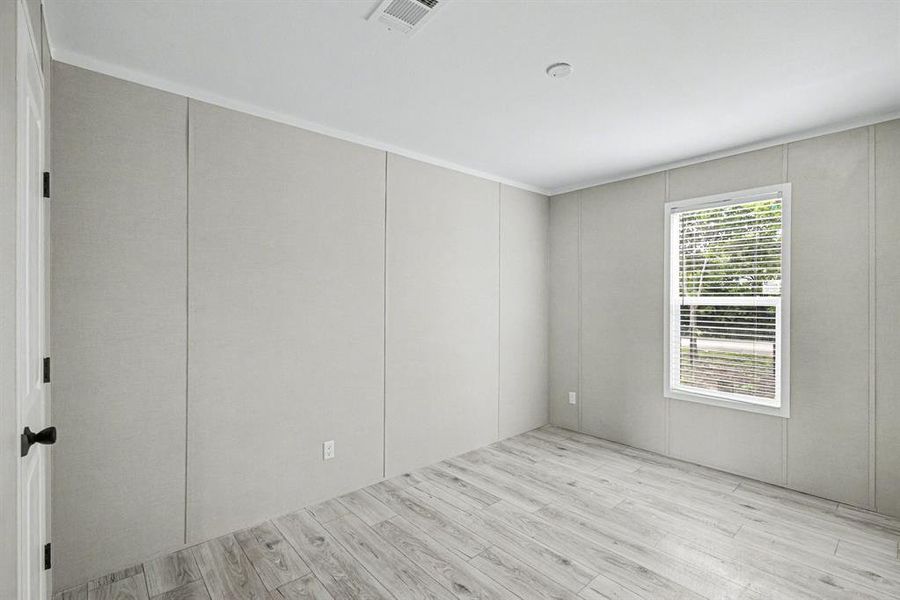 Neutral-toned interior room with wood-look flooring, white trim, panel-style walls, and a closet
