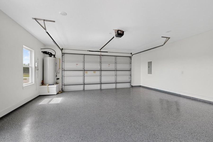 Garage with water heater, electric panel, and a garage door opener