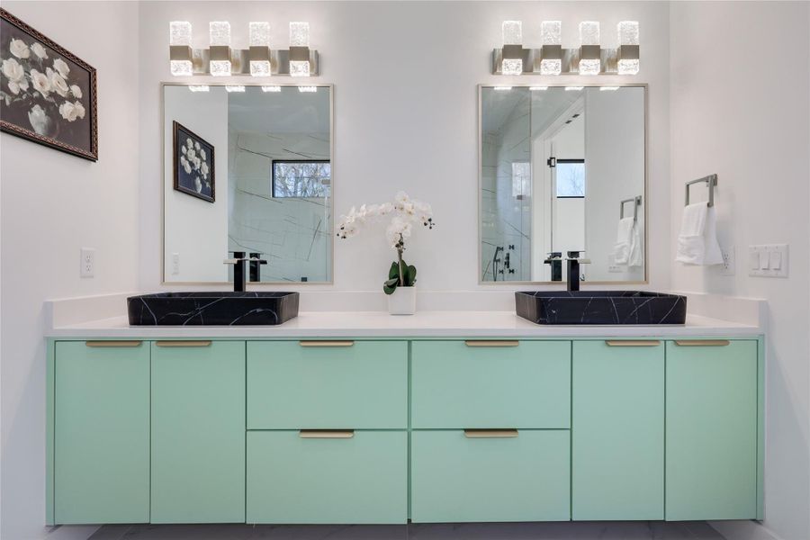 Full bathroom featuring double vanity and a marble finish shower