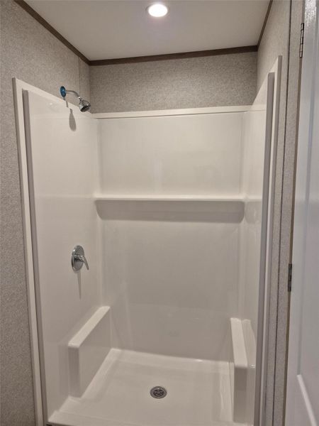Bathroom featuring a stall shower and crown molding