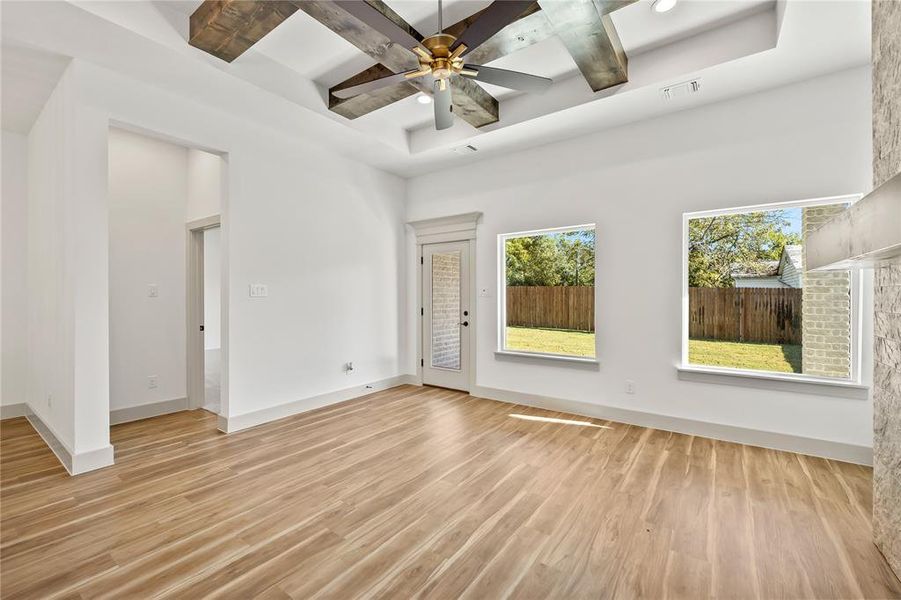 Spare room featuring coffered ceiling, beamed ceiling, light wood finished floors, and a ceiling fan