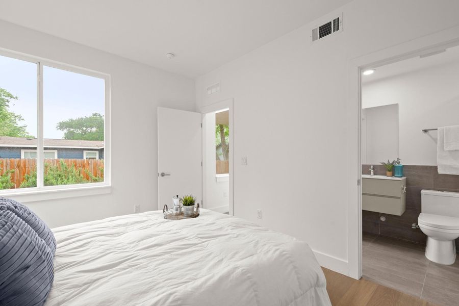 Bright interior space featuring a large window, light wood-finish flooring, and a crisp white color palette