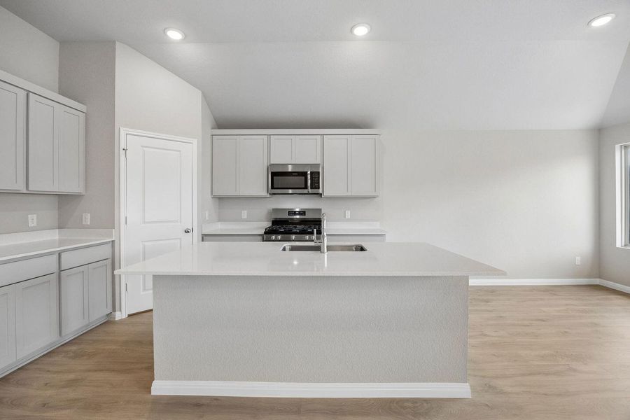A well-lit kitchen with sleek countertops and modern appliances offers ample space for culinary endeavors.