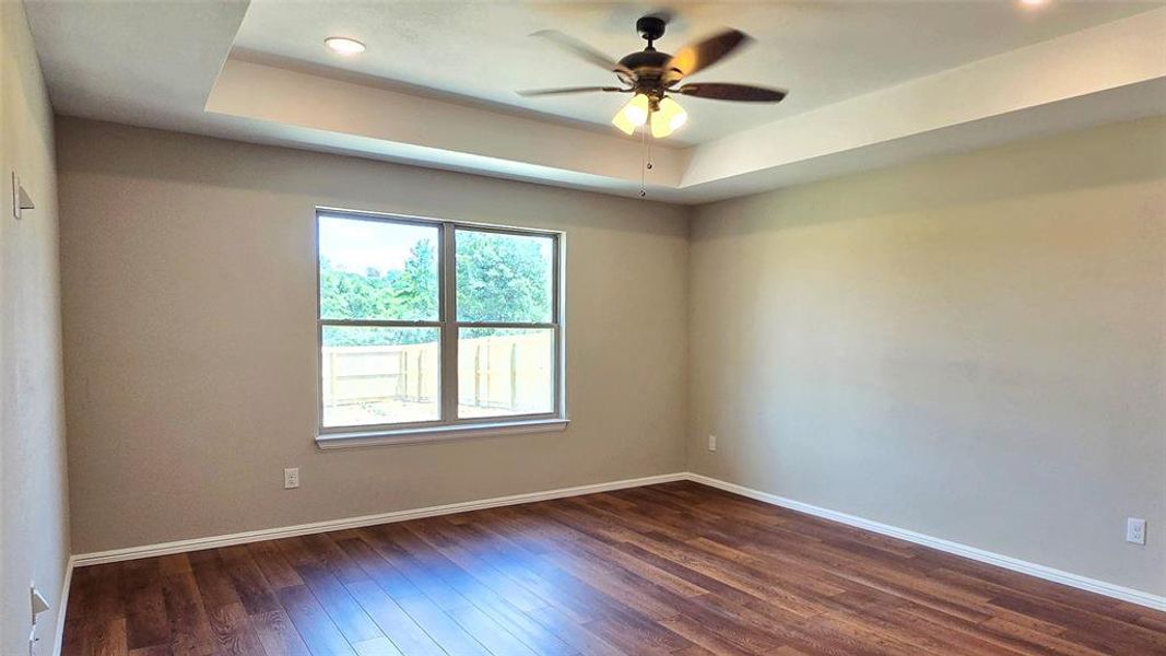 Empty room with dark wood finished floors, a raised ceiling, a ceiling fan, and recessed lighting