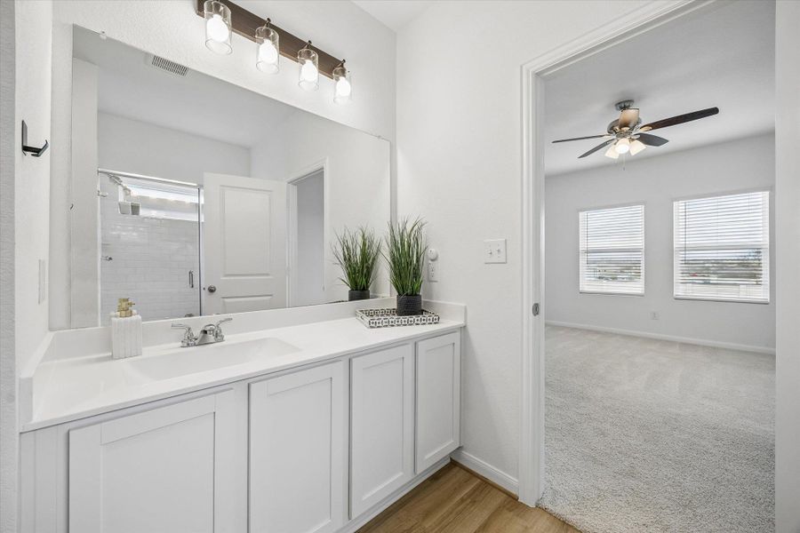 Full bathroom with vanity, light wood-style flooring, ceiling fan, a shower stall, and light carpet