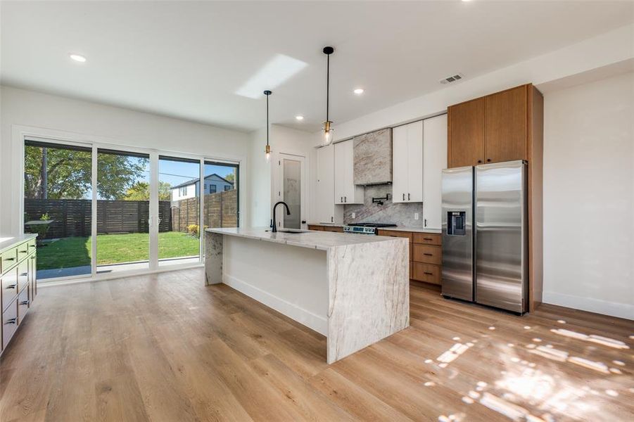 Kitchen with white cabinetry, stainless steel appliances, decorative light fixtures, recessed lighting, and backsplash