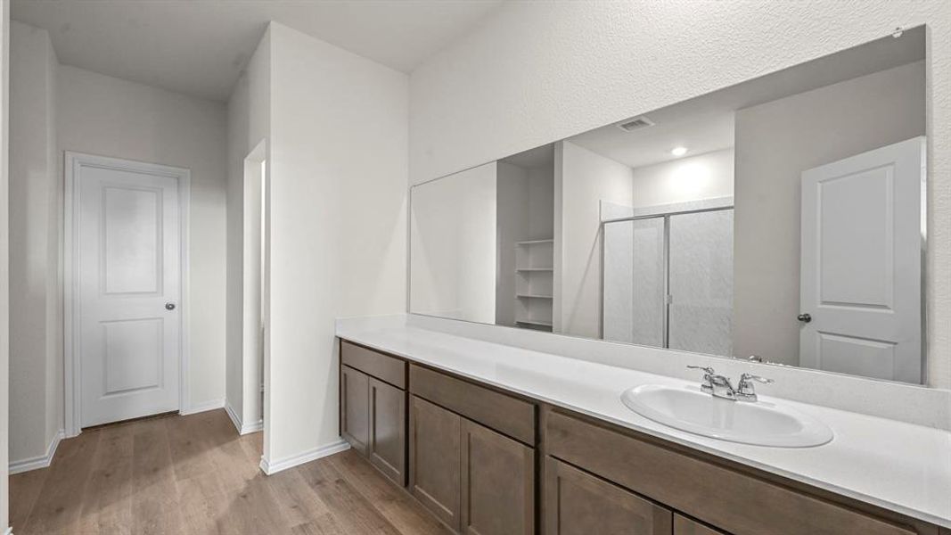 Bathroom vanity featuring an integrated sink, polished chrome faucet, and expansive wall-mounted mirror