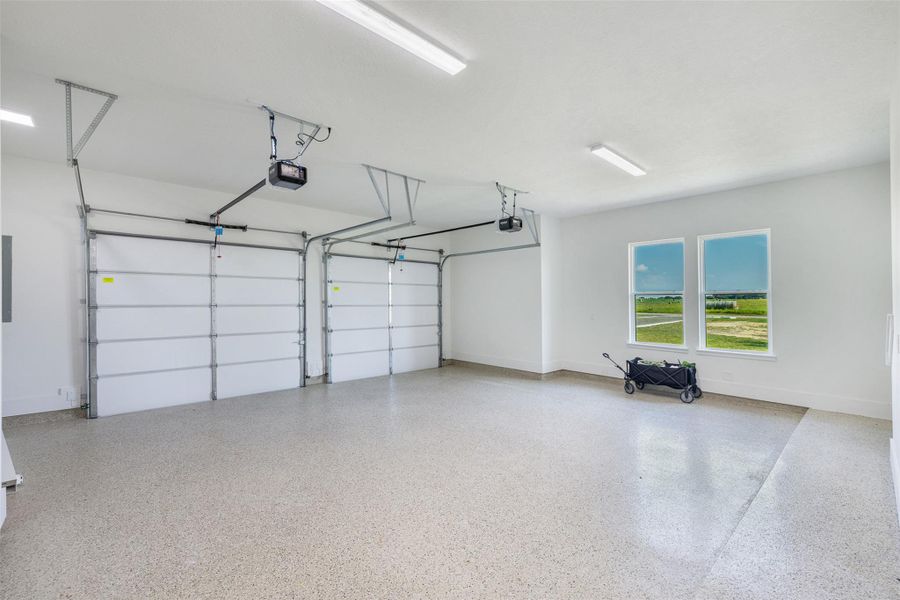Garage with baseboards and a garage door openers with epoxy coated flooring