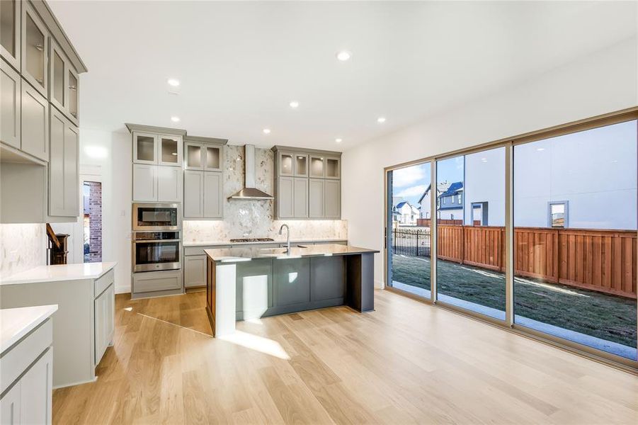 Kitchen featuring black microwave, wall chimney range hood, gray cabinets, and oven