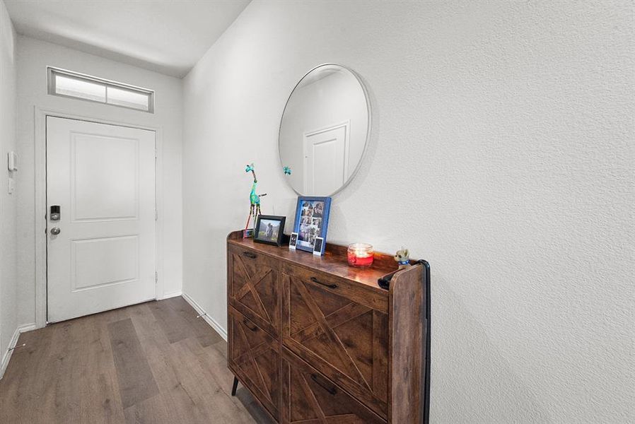 Entryway featuring wood-finish flooring, a white door with a transom window, and textured white walls