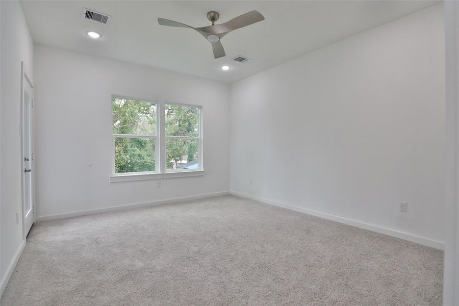 This bright, spacious ensuite features plush carpeting, a modern ceiling fan, and ample natural light, offering a serene view of the greenery outside. This bright, spacious ensuite features plush carpeting, a modern ceiling fan, and ample natural light, offering a serene view of the greenery outside.