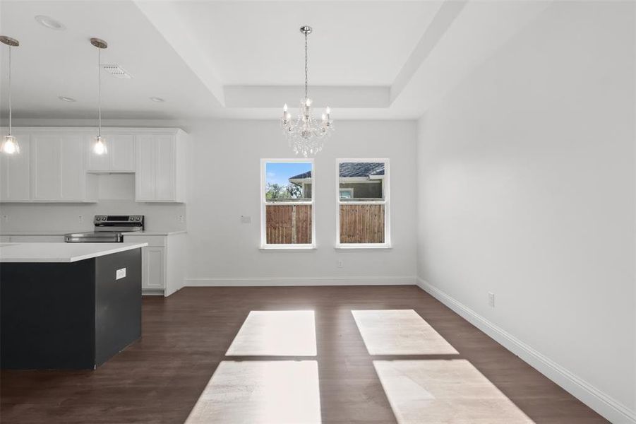 Kitchen featuring white cabinets, a raised ceiling, hanging light fixtures, dark hardwood / wood-style floors, and stainless steel electric range oven