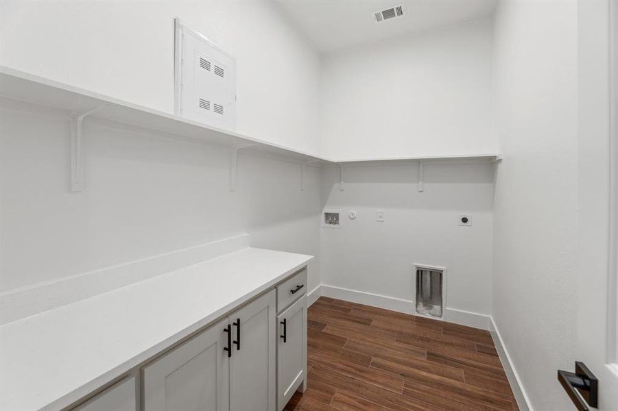 Clothes washing area featuring electric dryer hookup, visible vents, dark wood-style floors, baseboards, and laundry area