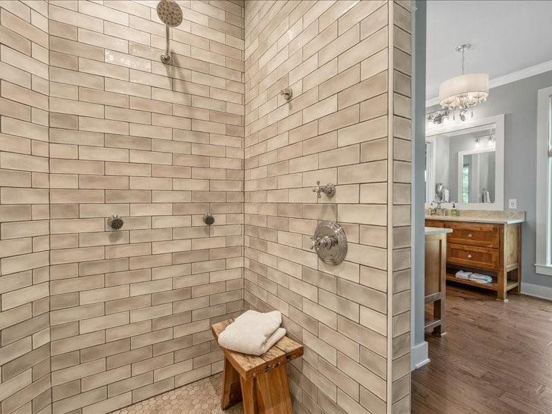 Large shower with handheld wand on one side and shower head on the other with spray features.