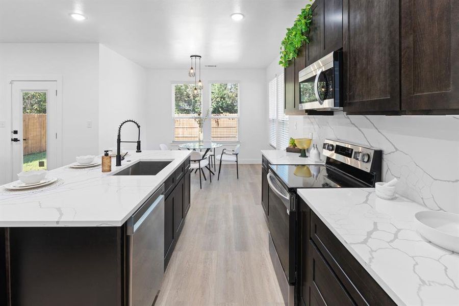 Kitchen with a wealth of natural light, sink, appliances with stainless steel finishes, and decorative light fixtures