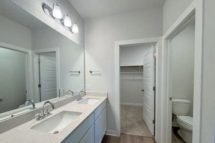 Full bath with wood finished floors, double vanity, and a spacious closet