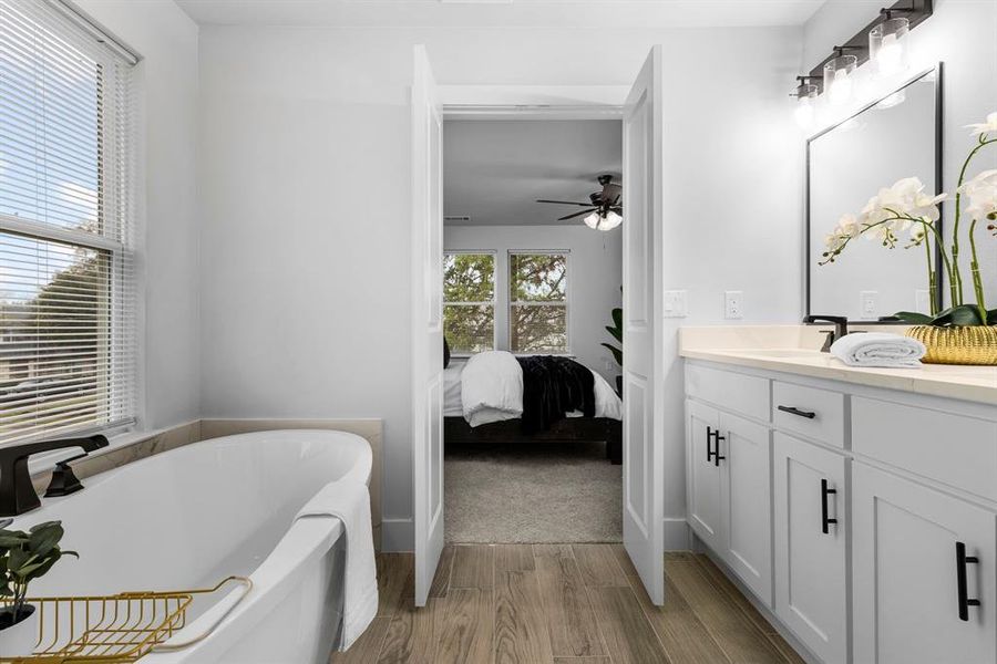 Bathroom featuring hardwood / wood-style flooring, ceiling fan, a bathtub, and vanity