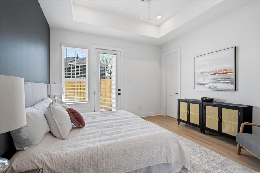 Duplex primary bedroom with high ceilings, large windows, and direct access to the backyard.