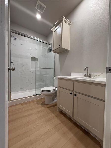 Full bathroom featuring a marble finish shower, vanity, light wood-style flooring, and recessed lighting
