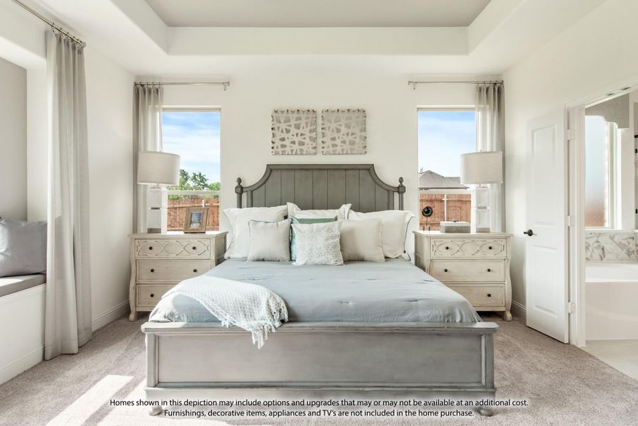 Master bedroom with tray ceiling, gray upholstered bed, two windows, and neutral carpet flooring