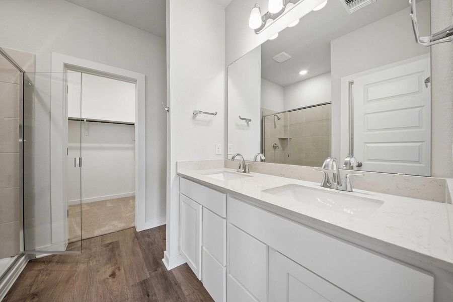 A well-appointed primary bathroom showcases a double vanity, elegant countertops, and a sleek glass-enclosed shower. A well-appointed primary bathroom showcases a double vanity, elegant countertops, and a sleek glass-enclosed shower.