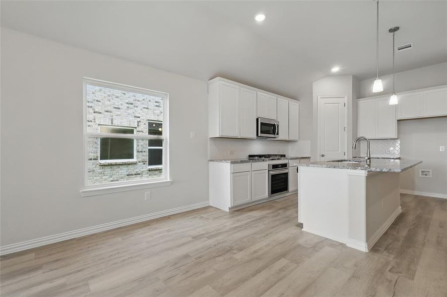 Kitchen with stainless steel appliances, a sink, tasteful backsplash, light stone counters, and recessed lighting