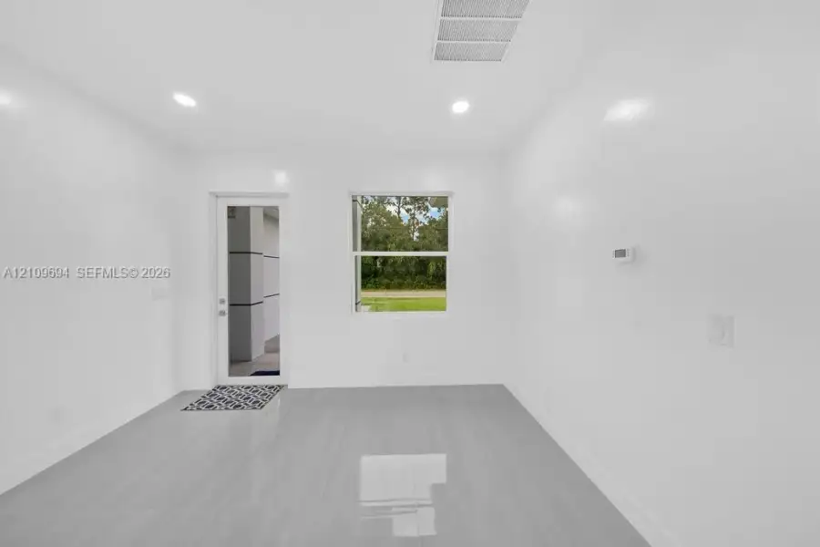 Interior space featuring neutral wall paint, polished tile flooring, recessed ceiling lighting, and a single-light glass panel door