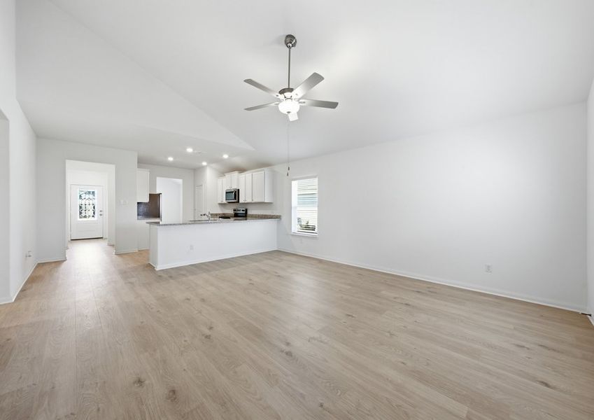 Open-concept family room featuring a chandelier light fixture, wood-look vinyl flooring, and a sightline into the kitchen. Open-concept family room featuring a chandelier light fixture, wood-look vinyl flooring, and a sightline into the kitchen.