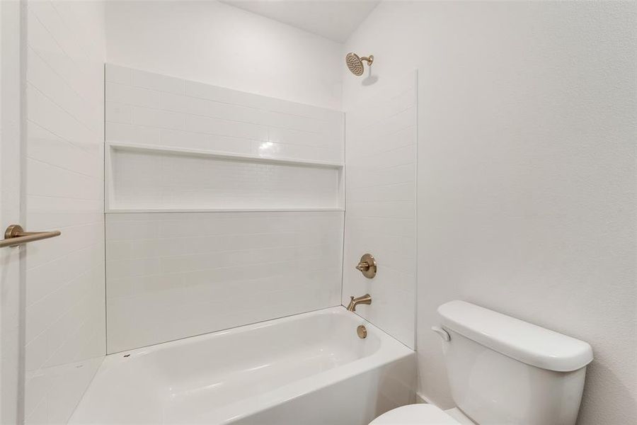 Bathroom featuring tiled shower / bath and toilet