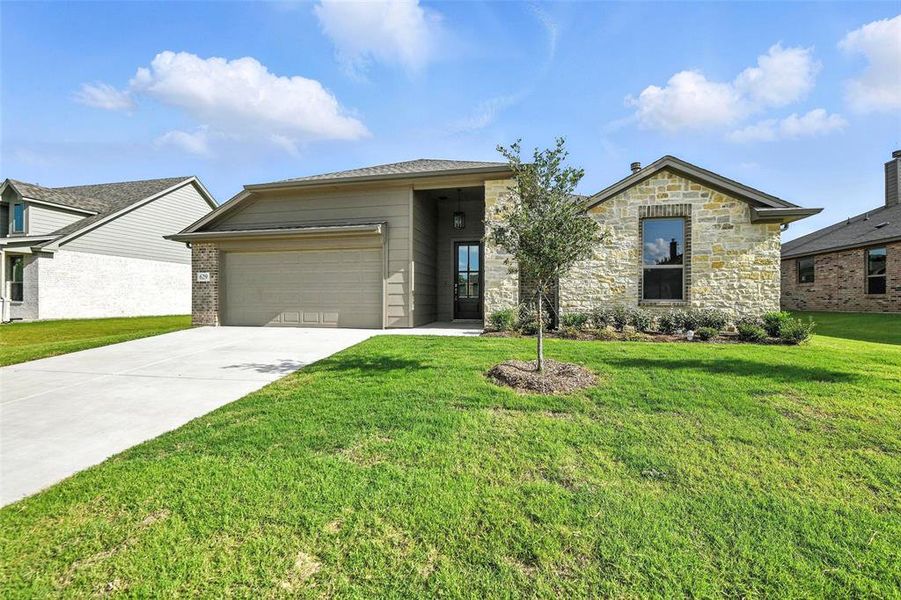 View of front of home featuring driveway, a garage, a front yard, and stone siding
