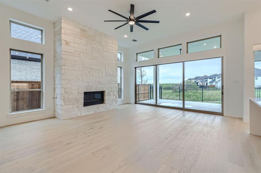 Unfurnished living room with ceiling fan, a fireplace, a high ceiling, and a wealth of natural light