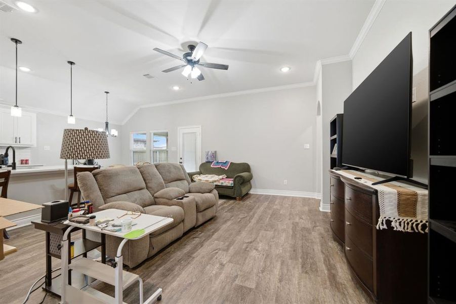 Living room featuring crown molding, light wood-type flooring, ceiling fan, recessed lighting, and vaulted ceiling