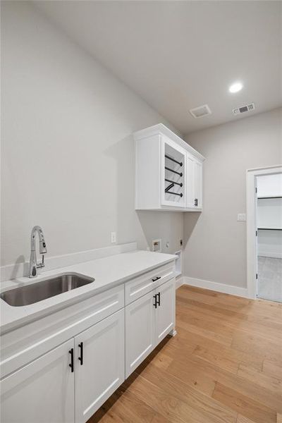 Laundry room featuring cabinets, sink, hookup for an electric dryer, light hardwood / wood-style flooring, and hookup for a washing machine