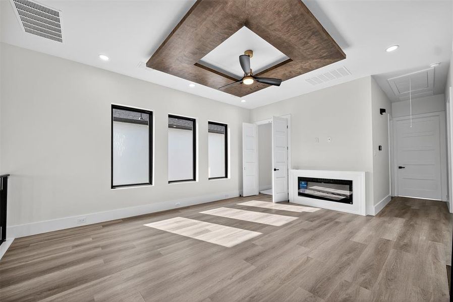 Unfurnished living room with a raised ceiling, attic access, a ceiling fan, light wood finished floors, and recessed lighting