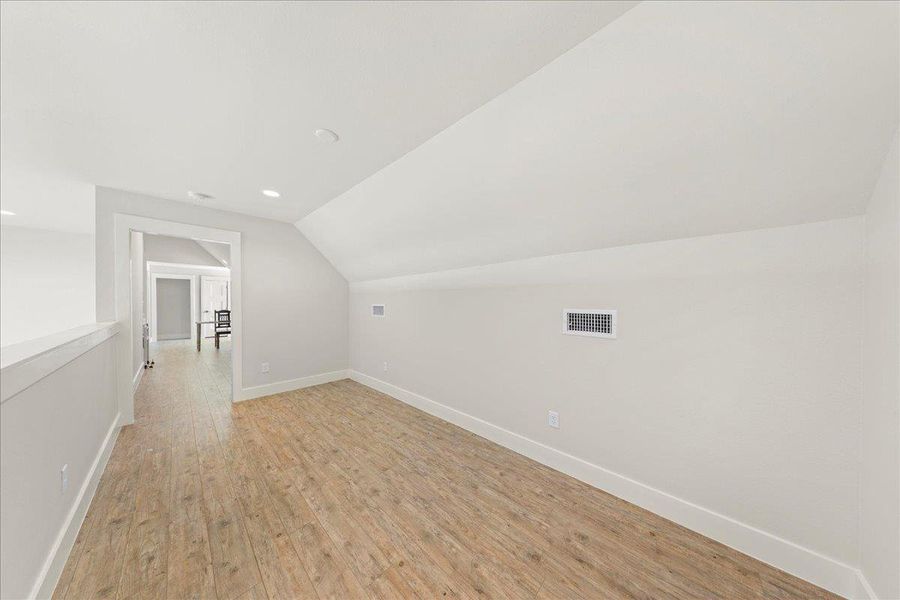 Additional living space with vaulted ceiling, light wood finished floors, and recessed lighting Additional living space with vaulted ceiling, light wood finished floors, and recessed lighting